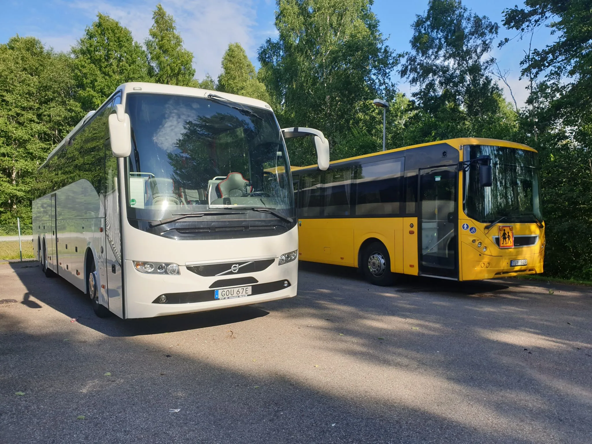 Två av Bergslagsbuss fordon, en turistbuss och en linjebuss, uppställda utomhus